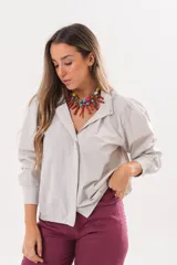 Camisa beige a rayas finas de manga larga, con cuello camisero y cierre frontal oculto.