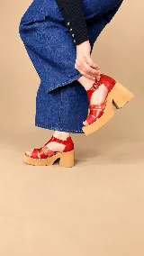 Sandalias de cuero color suela, con plataforma alta y taco ancho. Presentan tiras cruzadas en el empeine con mix de texturas y cierre de hebilla metálica en el tobillo.