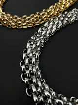 Collar de cadena gruesa de eslabones entrelazados en tono dorado, con cierre de mosquetón y cadena de alargue.