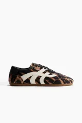 Calzado deportivo con cordones, diseño de estampado animal print de tigre y detalles en blanco y negro, con suela de goma acanalada.
