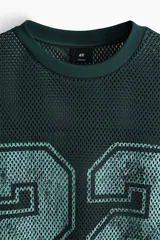 Remera de malla color verde oscuro, de corte oversized y manga corta, con cuello redondo y gran estampado frontal con el número 22 en tono celeste.