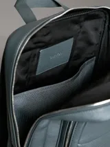 Mochila Calvin Klein color verde oscuro, de cuero sintético con textura micro pebble. Tiene un bolsillo frontal con cierre, asa de mano y correas acolchadas ajustables. Interior con funda acolchada para laptop, bolsillo con cierre y portabolígrafos.