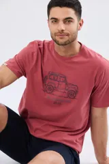 Remera de algodón color salmón con mangas cortas y cuello redondo. Cuenta con un diseño estampado y bordado en el pecho de un vehículo todoterreno acompañado del texto "The Adventure Club Legacy".