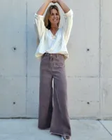 Jean de corte wide leg en color gris oscuro con efecto lavado. Presenta tiro alto, cierre frontal con botón y ruedo deshilachado.