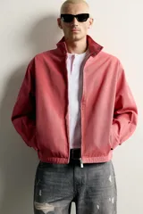 Cazadora relaxed fit de algodón lavado color bordó, con cuello subido y cierre frontal de cremallera de doble dirección. Cuenta con bolsillos ocultos en las costuras de la cadera y mangas largas con puños abotonados.