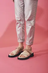 Sandalias de plataforma con tiras cruzadas en el empeine y ajuste de velcro en el tobillo. Presentan una combinación de colores beige y marrón, con suela de goma negra.