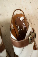 Sandalias de cuero color tostado y blanco, con plataforma track y hebilla metálica.