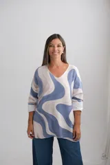 Sweter de punto con diseño de ondas abstractas en tonos azul y beige, escote en V y mangas largas con puños doblados.