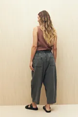 Pantalón de algodón color gris oscuro, estilo baggy o ancho, con cintura elástica y cordón ajustable. Presenta costuras marcadas que definen paneles en la pierna y puños ajustados en el tobillo.