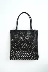 Cartera tipo tote de cuero sintético color negro, decorada con tachas metálicas plateadas de distintos tamaños dispuestas de forma degradada. Cuenta con doble asa de hombro.