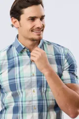 Camisa de manga corta con estampado de cuadros en tonos celestes, azules, blancos y verdes, con cierre frontal de botones y bolsillo ojal en el pecho.