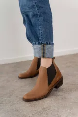 Bota corta de cuero color marrón con elásticos laterales, taco bajo y punta redondeada.