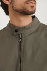 Campera estilo bomber color verde oscuro, con cierre metálico, dos bolsillos externos con cierre y un bolsillo interno.