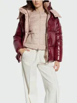 Campera corta acolchada de plumas, con acabado brillante. Presenta un diseño bicolor: exterior en color borgoña/vino y forro interior en rosa pálido. Tiene capucha y cierre frontal.