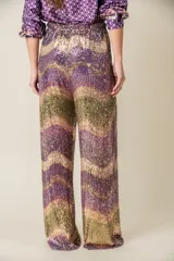Pantalón italiano de corte palazzo, con cintura elastizada y forro de viscosa. Cubierto de lentejuelas con diseño de ondas en tonos violeta, dorado y verde.