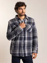 Camisa tipo campera de franela con estampado a cuadros en tonos azul, gris y blanco. Cuenta con forro interior de sherpa, cierre frontal con botones, cuello clásico y bolsillo en el pecho.