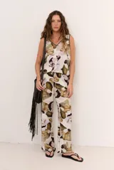 Pantalón largo beige de corte holgado con estampado floral en tonos marrones y violetas, y cintura con cordón ajustable.