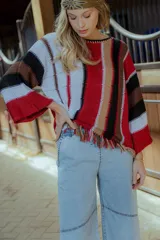 Sweater tejido en hilado 100% algodón con diseño a rayas verticales en tonos rojo, blanco, marrón y negro. Presenta flecos en el ruedo y bordados en el escote.