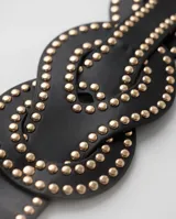 Cinto elástico negro de diseño entrelazado decorado con tachas doradas.