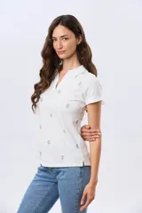 Remera polo de algodón color beige con mangas cortas, escote en V y cuello camisero. Presenta delicados mini bordados florales distribuidos en toda la prenda.