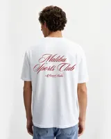 Remera blanca de algodón con cuello redondo y estampado en la espalda con la frase "Malibu Sports Club by Rona Studio" en color rojo.