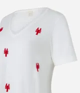Remera de mangas cortas color crema, confeccionada en tejido flamé, con escote en pico y bordado delantero de langostas rojas.