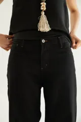 Pantalón de corte recto y tiro medio con costuras a la vista, bolsillos delanteros y traseros, y un detalle de pin de la marca en el ruedo.
