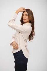 Camisa de corte clásico con cuello camisero, cierre frontal de botones y bolsillo en el pecho. Presenta un diseño de rayas verticales finas en tonos beige y blanco.