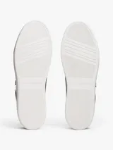Zapatillas de corte bajo estilo tenis, confeccionadas en piel color negro. Presentan suela de goma blanca, detalle metalizado en el talón, ojal superior dorado y monograma TH metálico en el lateral.