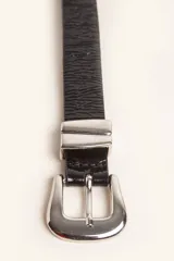 Cinturón de cuero liso color marrón oscuro con hebilla plateada y pasador metálico decorativo.