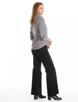 Camisa de corte clásico con estampado de rayas verticales en blanco y negro. Presenta cuello con solapa, escote en V, cierre frontal con botones perlados y apliques de perlas decorativas en la parte superior delantera. Posee mangas tres cuartos con puños abotonados.