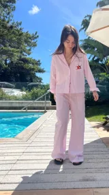 Camisa de algodón a rayas finas blancas y celestes, con cuello sastrero, botones de nácar y bolsillo frontal con bordado de estrella de mar en tonos azules.