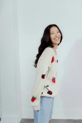 Buzo de lana merino color crema con diseño tejido de frutillas y cerezas en tonos rojos y bordó. Presenta cuello redondo, mangas largas y un corte holgado.