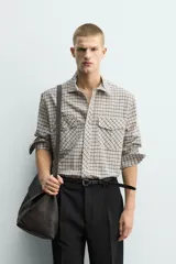Camisa de corte relajado con estampado de cuadros, cuello solapa, manga larga con puños abotonados y bolsillos frontales de plastrón con solapa. Cierre frontal con botones a presión.