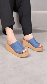 Zuecos con plataforma corrida de yute y suela de goma, capellada ancha de color marfil con textura símil serpiente y diseño abierto en la punta.