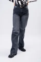 Jean de corte wide leg con tiro alto, en color negro gastado. Presenta un diseño de cinco bolsillos, cierre frontal con botón y cremallera, y trabillas para cinturón.