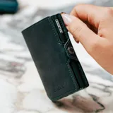 Billetera de cuero genuino color verde con tarjetero de aluminio incorporado. Posee un sistema de deslizamiento para tarjetas, protección RFID, compartimento para billetes y cierre con broche a presión.