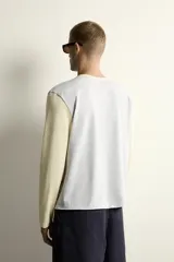 Camiseta de corte relajado con diseño color block, cuerpo en gris melange y mangas largas y cuello redondo en amarillo pastel.