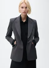 Chaqueta de corte recto con estampado de micro pata de gallo, cuello con solapa y cierre frontal de botones. Presenta mangas largas con puños abotonados, bolsillos delanteros con solapa y abertura posterior en el bajo.