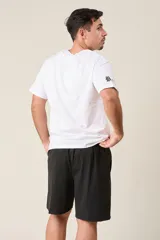 Bermuda deportiva color verde militar, de corte suelto, confeccionada en nylon. Cuenta con cintura elástica, cordón de ajuste, detalles de líneas en los costados y bolsillos con cierre.