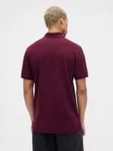 Polo de manga corta color verde oscuro, con cuello clásico, cierre frontal de dos botones y logo del oso Brannan bordado en el pecho.