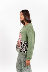 Sweater de punto color verde, tejido y bordado a mano, con diseño gráfico artesanal en el frente y mangas largas.