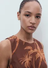 Mono largo marrón con estampado de palmeras, diseño sin mangas, cuello redondo, detalles cut-out en los laterales y un nudo decorativo en la parte delantera.