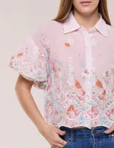 Camisa de gasa rosa con estampado floral y bordados, cuello camisero, mangas cortas abullonadas y cierre frontal de botones.