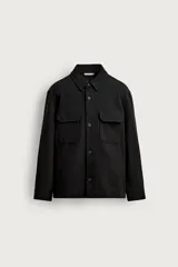 Sobrecamisa relaxed fit de color negro, confeccionada en tejido elástico con textura. Cuenta con cuello solapa, manga larga con puños abotonados, bolsillos de plastrón con solapa en el pecho, bolsillos laterales de vivo en la cadera y cierre frontal de botones.