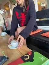 Sweater tejido de lana color negro con diseño de esqueleto en rojo en el frente.