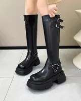 Bota bucanera negra de cuero sintético con plataforma track y caña alta con hebillas decorativas.
