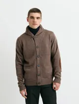 Cardigan de punto color marrón con cuello esmoquin, cierre frontal con botones y presilla superior. Presenta mangas largas con coderas en contraste y bolsillos frontales de ribete.