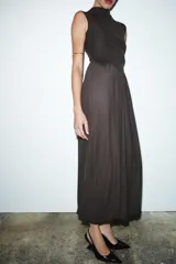 Vestido largo sin mangas con cuello subido, confeccionado con una parte superior lisa y falda de tul con caída fluida. Cuenta con cierre de cremallera oculta en la espalda.