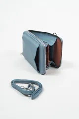 Bandolera verde con textura granulada, cierre superior con cremallera y correa larga ajustable para llevar al hombro o cruzada.